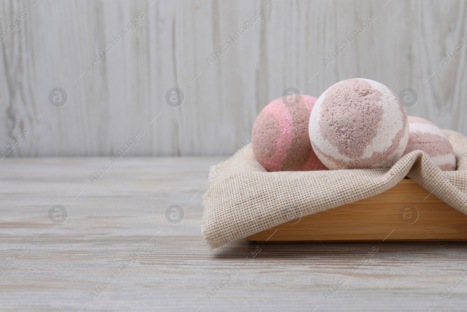 Photo of Bath bombs in crate on wooden table, space for text
