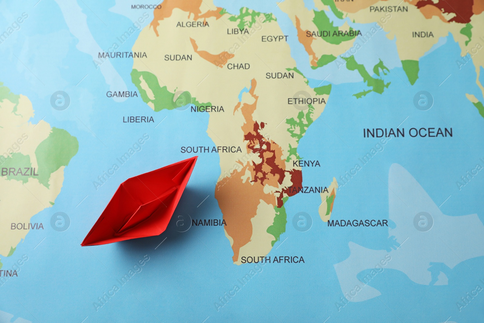 Photo of Red paper boat on world map, top view