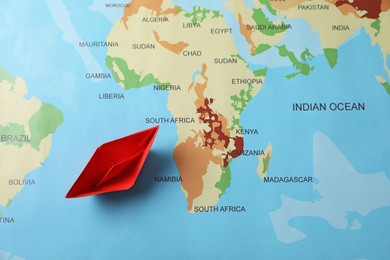 Red paper boat on world map, top view