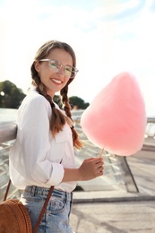 Young woman with cotton candy outdoors on sunny day