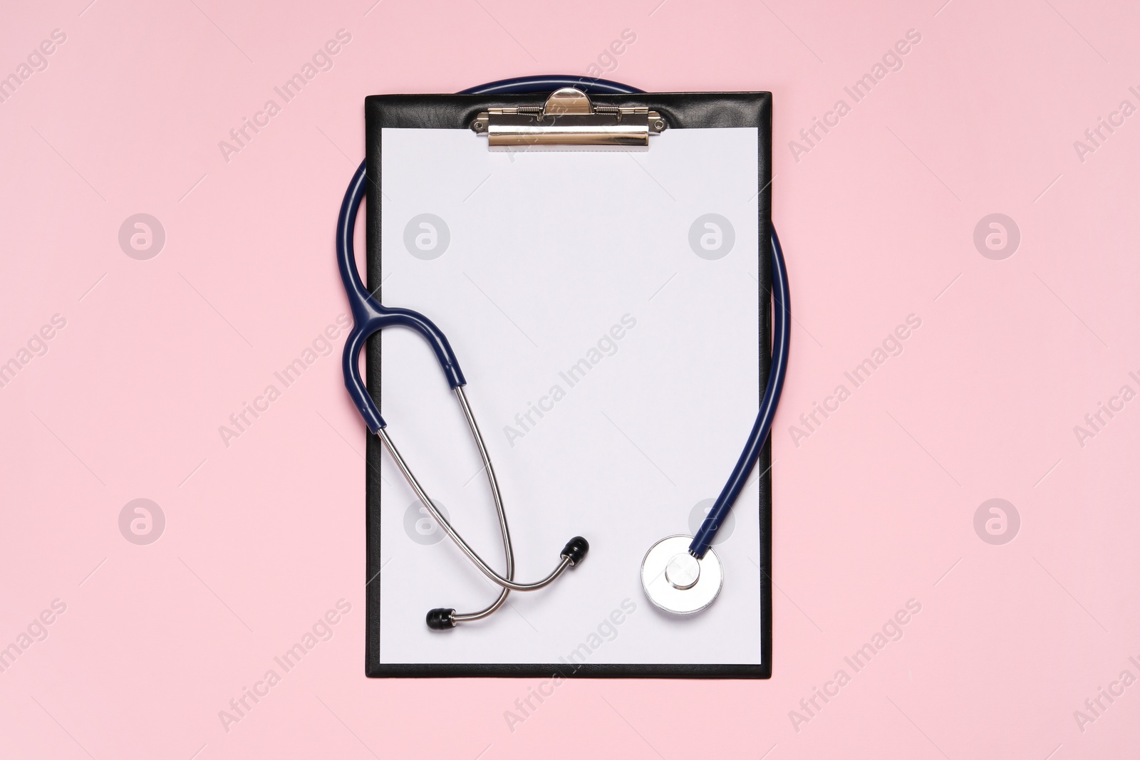 Photo of Stethoscope and clipboard on pink background, top view. Medical tool