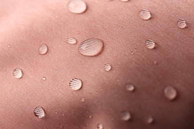 Photo of Pink waterproof fabric with water drops as background, closeup