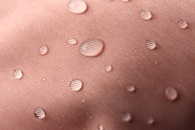 Pink waterproof fabric with water drops as background, closeup