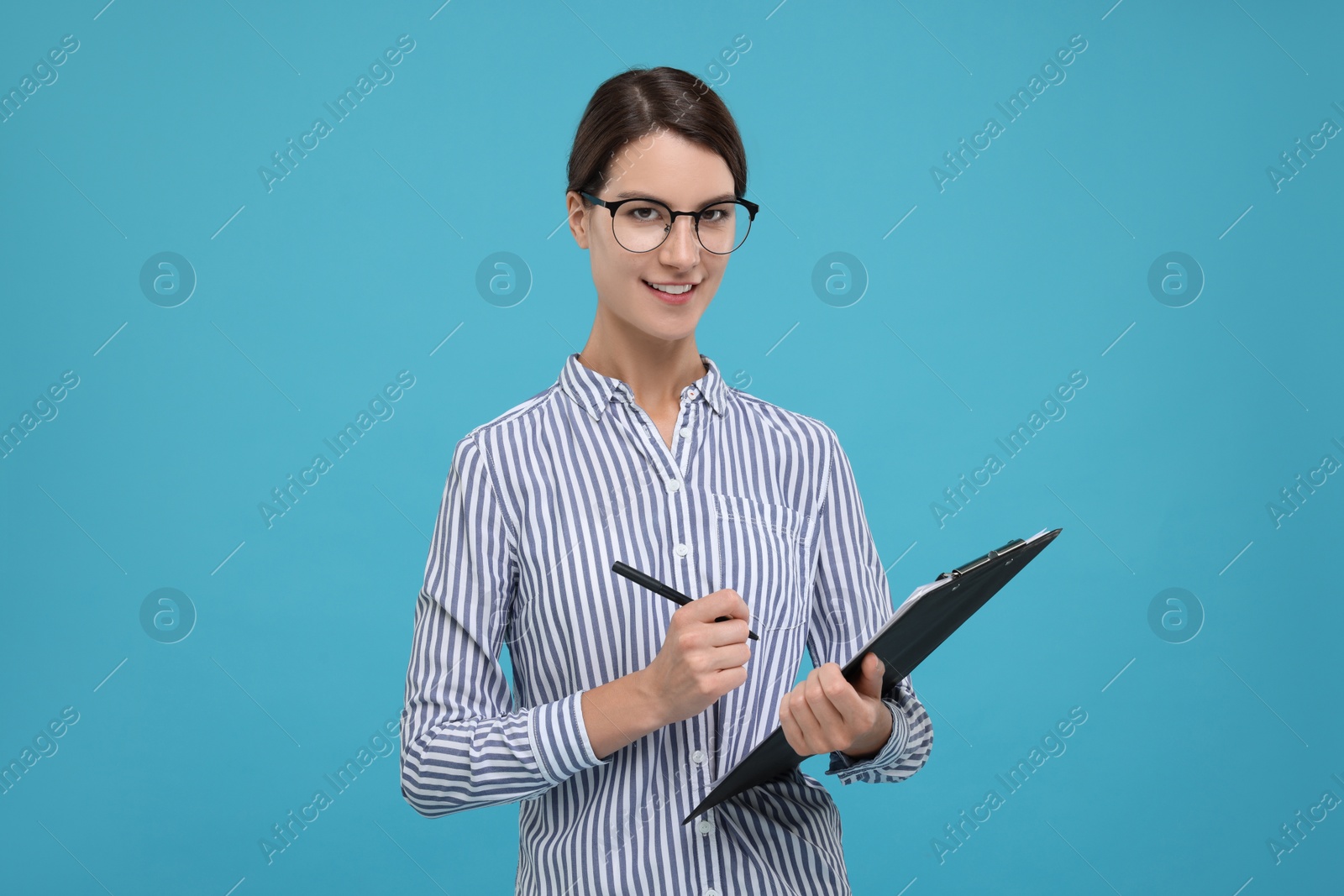 Photo of Young secretary with clipboard and pen on light blue background