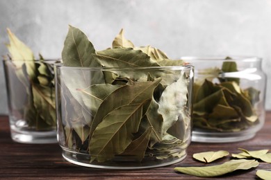 Photo of Bay leaves in glass jars on wooden table