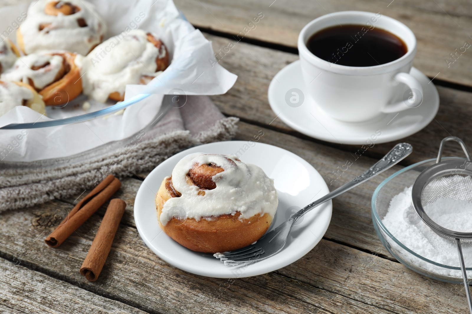 Photo of Tasty cinnamon rolls with cream served on wooden table