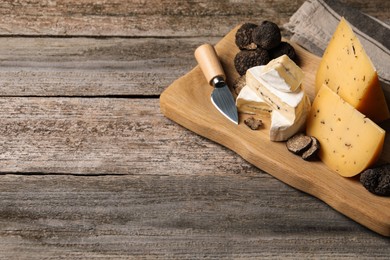 Different types of cheese, knife and truffles on wooden table, space for text