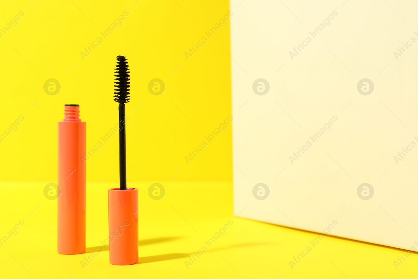 Photo of Mascara on yellow background, space for text. Makeup product