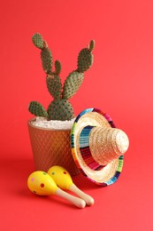 Mexican sombrero hat, cactus and maracas on red background