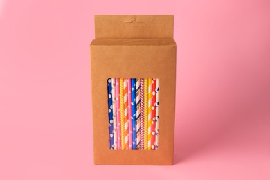 Box with many paper drinking straws on pink background