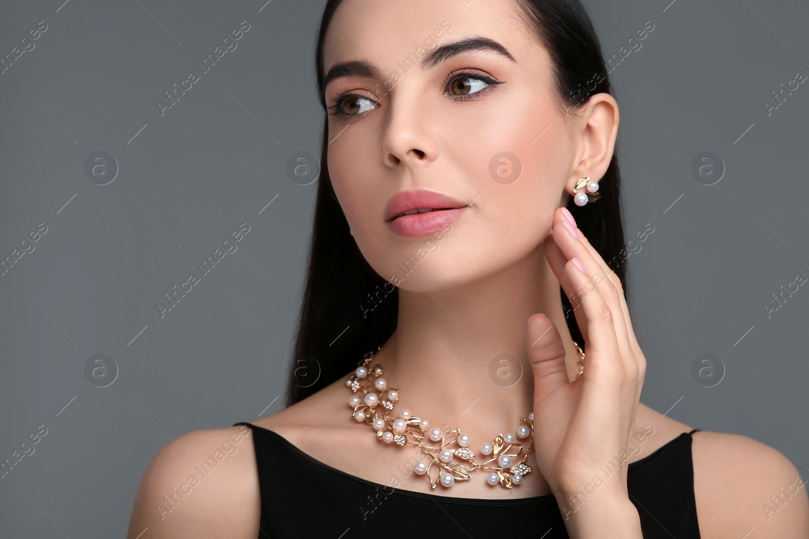 Photo of Beautiful young woman with elegant jewelry on dark grey background