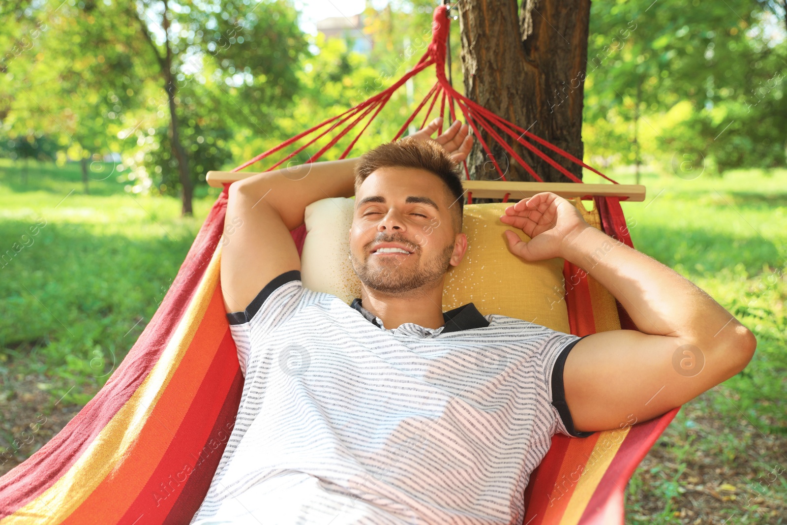 Photo of Young man resting in comfortable hammock at green garden