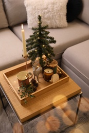 Photo of Composition with decorative Christmas tree and reindeer on wooden tray near sofa