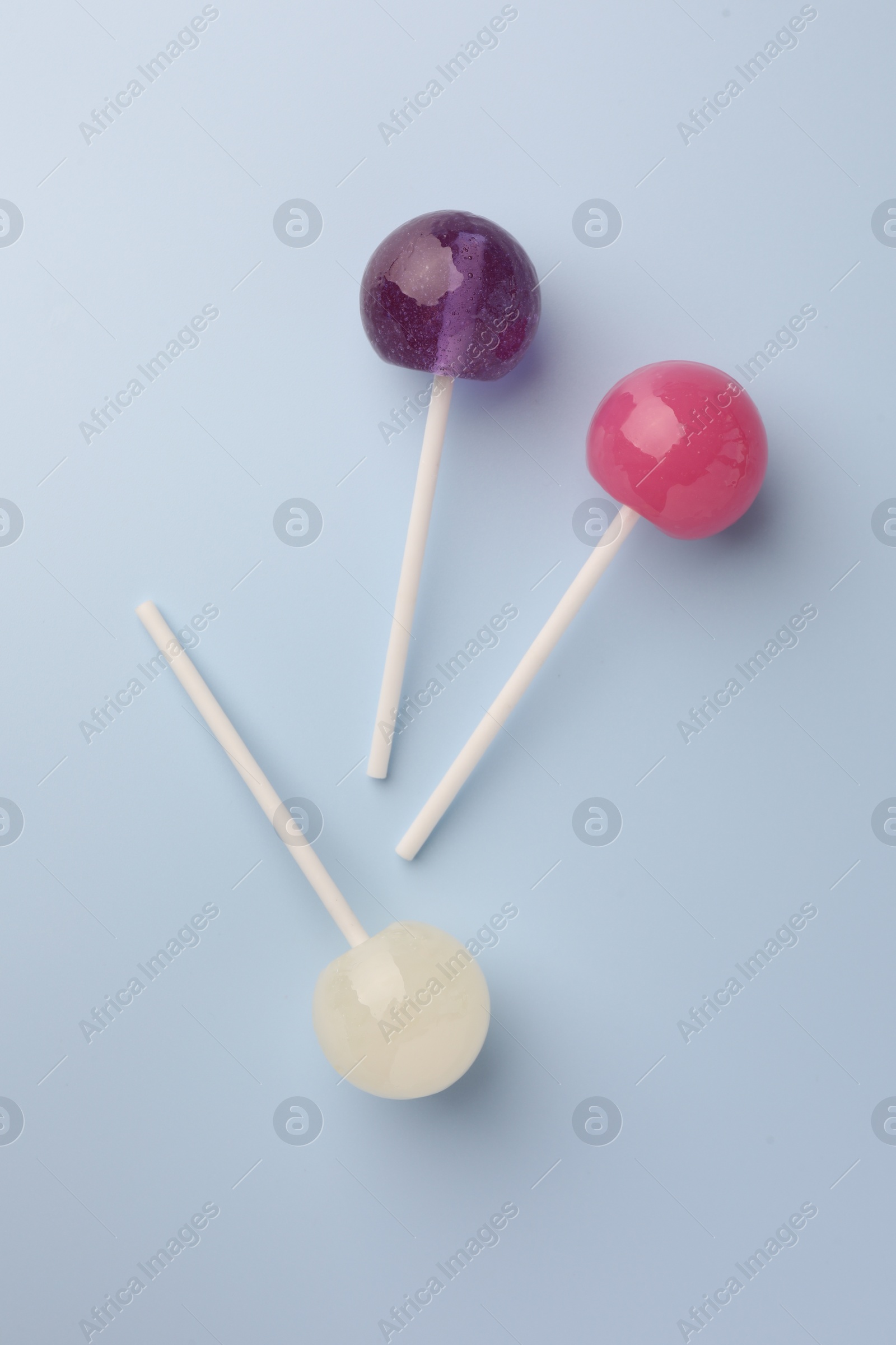 Photo of Tasty lollipops on light blue background, flat lay