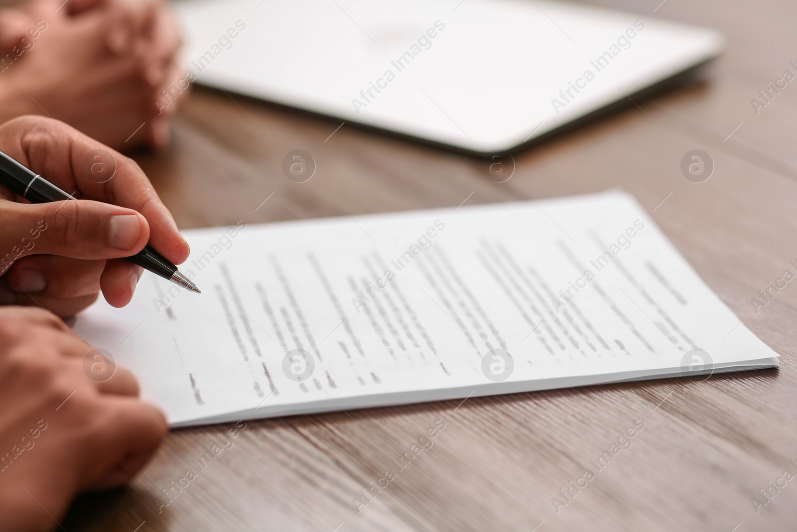 Photo of Notary helping couple with paperwork at wooden table, closeup