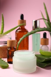 Jar of natural gel and fresh aloe on pink background