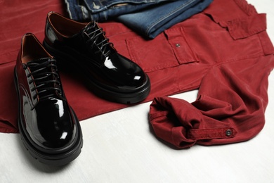 Photo of Stylish female shoes, shirt and jeans on white table, closeup