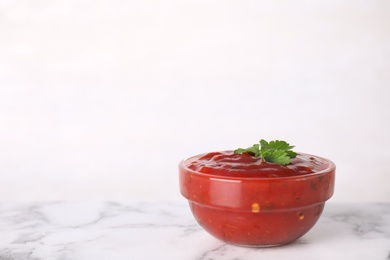 Photo of Bowl of hot chili sauce with parsley on table against white background. Space for text