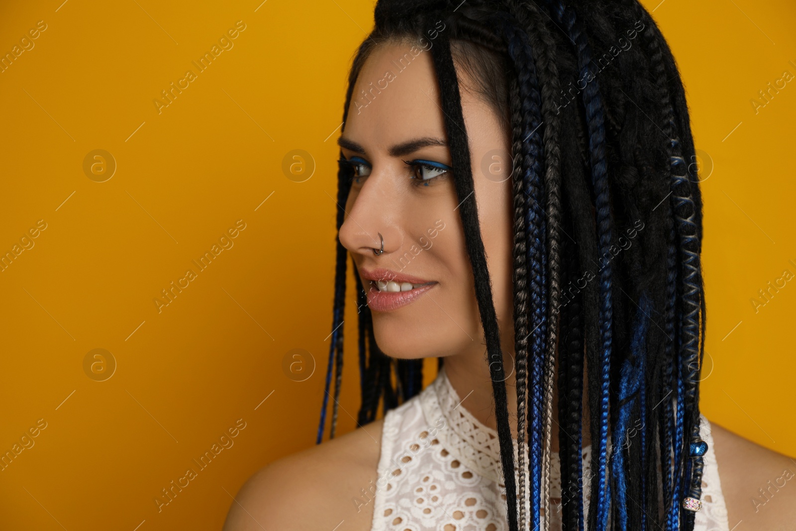 Photo of Beautiful young woman with nose piercing and dreadlocks on yellow background. Space for text