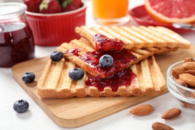 Photo of Delicious breakfast with toasted bread, jam and berries on white table, closeup