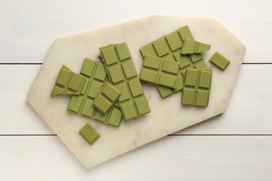 Photo of Pieces of tasty matcha chocolate bars on white wooden table, top view