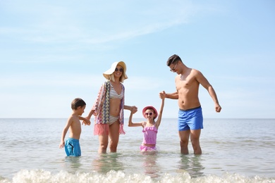 Happy family playing in water at beach on sunny day