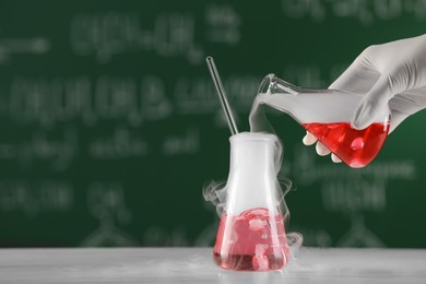 Scientist working with laboratory glassware at white table, closeup view with space for text. Chemical reaction