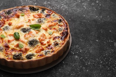 Photo of Delicious homemade quiche with salmon and broccoli on black table, space for text