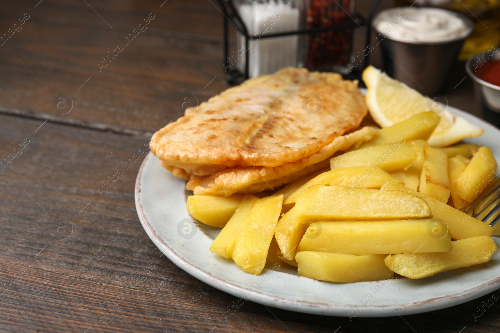 Photo of Delicious fish and chips on wooden table, closeup