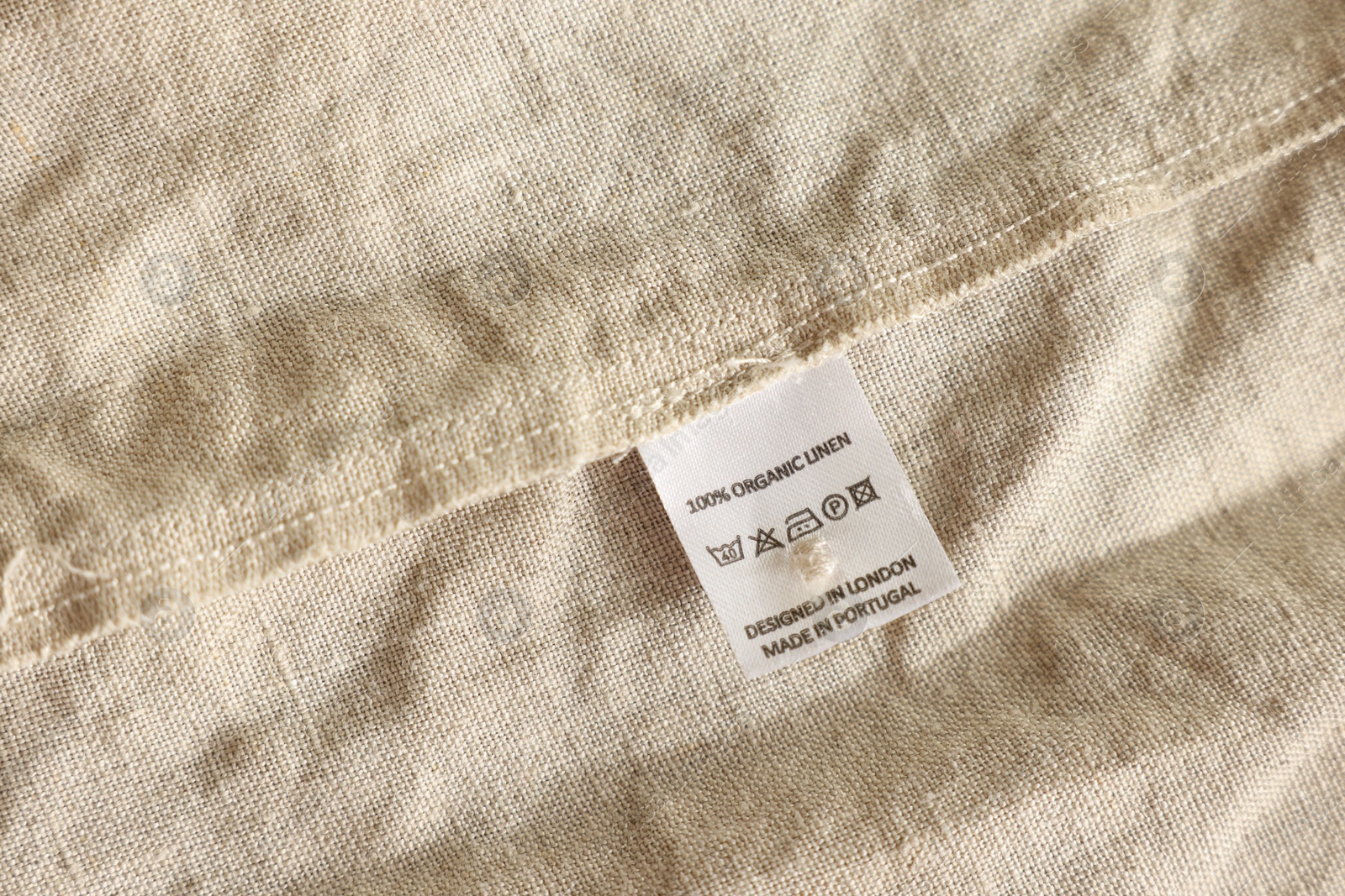 Photo of Clothing label on beige garment, closeup view