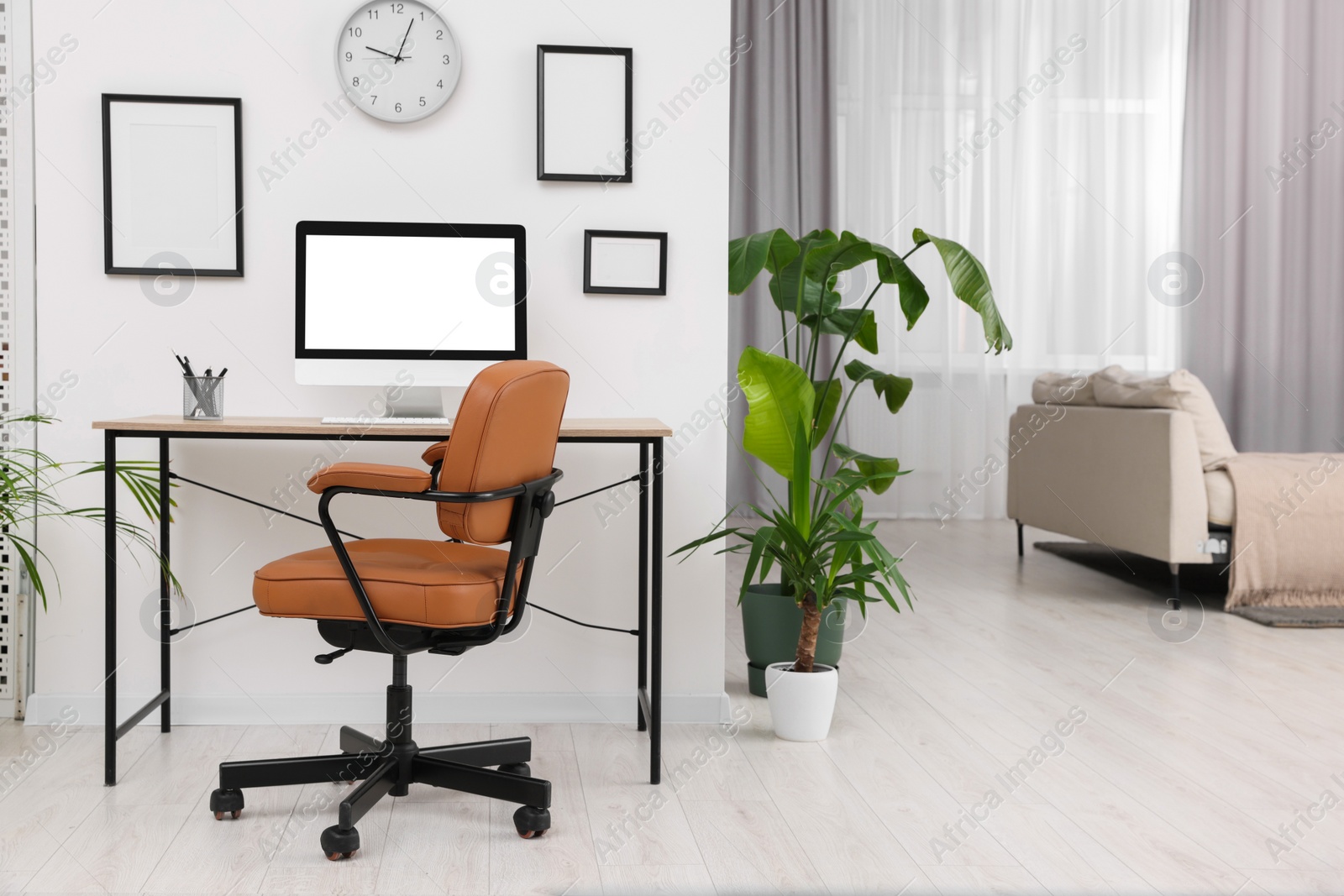 Photo of Stylish room interior with comfortable office chair, desk and houseplants