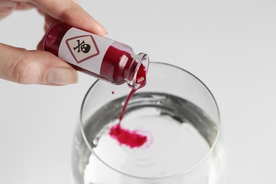 Photo of Woman pouring poison into glass of water on white background, closeup