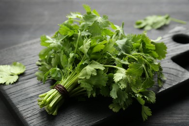 Photo of Bunch of fresh coriander on black wooden table, closeup