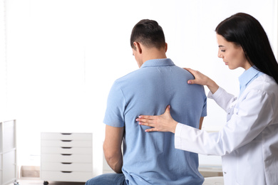 Photo of Professional orthopedist examining man in medical office