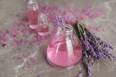 Photo of Bottles with aromatic lavender oil on grey table