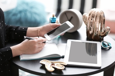 Photo of Female blogger using smartphone at table indoors, closeup