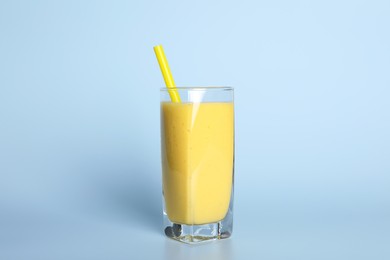 Photo of Glass of tasty smoothie with straw on light blue background