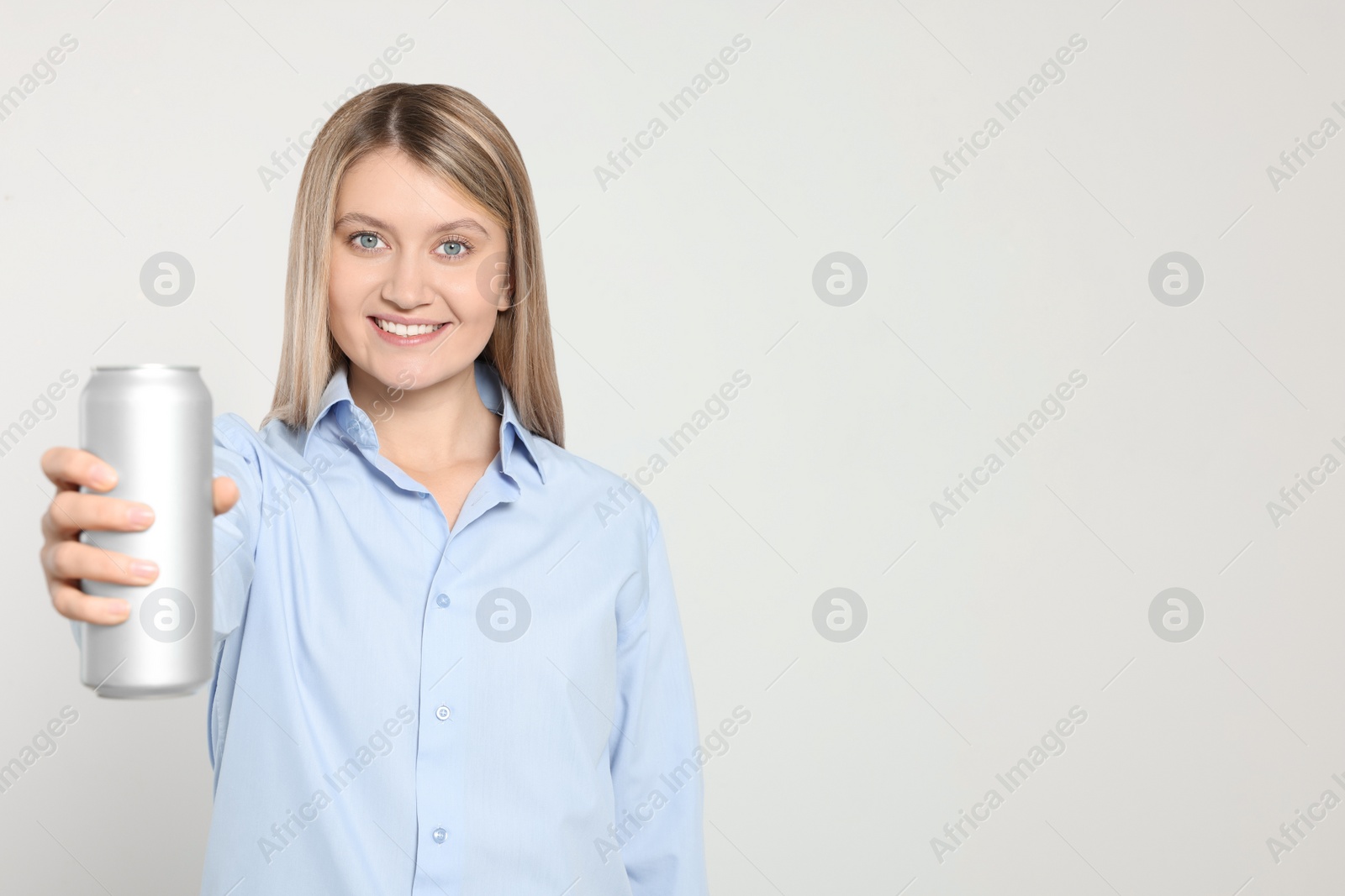 Photo of Beautiful happy woman holding beverage can on light background. Space for text