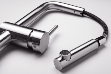 Photo of Modern pull out kitchen faucet on grey background, closeup