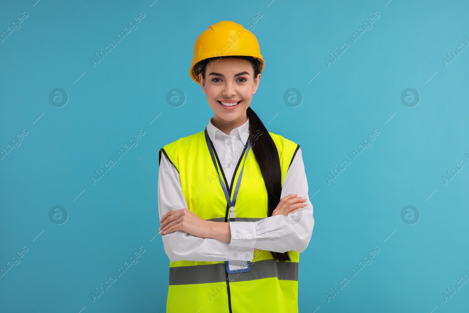 Photo of Engineer with hard hat and badge on light blue background