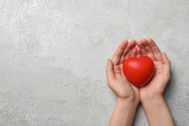 Photo of Woman holding heart on grey stone background, top view with space for text. Donation concept
