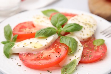 Photo of Delicious Caprese salad with herbs on plate, closeup