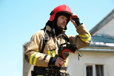 Firefighter in uniform with helmet and mask outdoors, low angle view