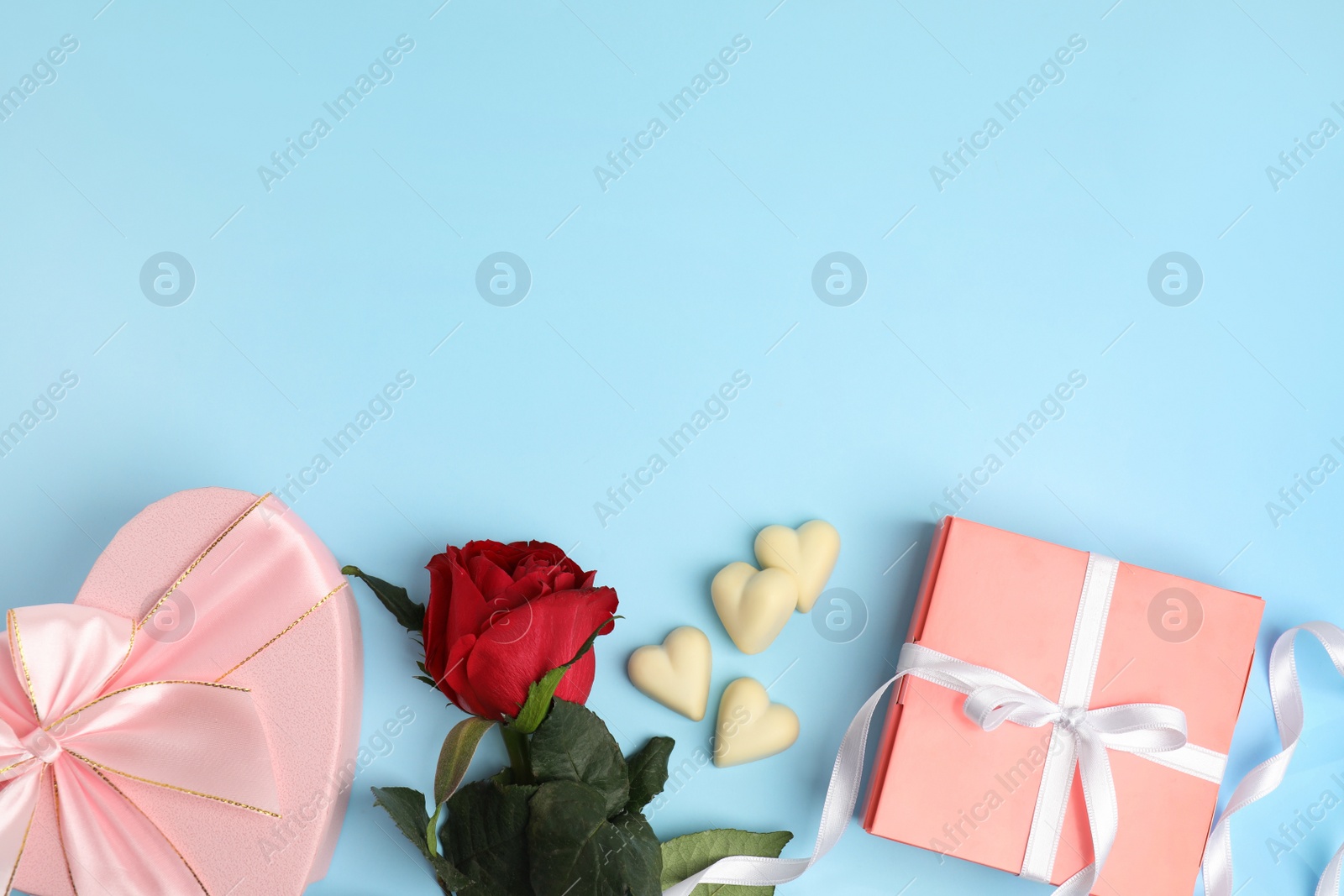 Photo of Flat lay composition with heart shaped chocolate candies on light blue background, space for text. Valentine's day celebration