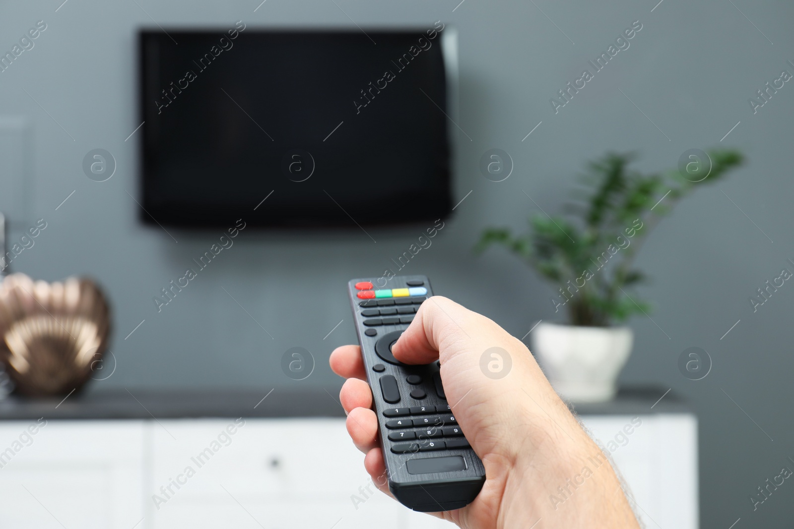 Photo of Man switching channels on plasma TV with remote control at home