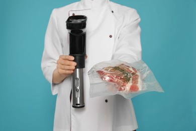 Photo of Chef holding sous vide cooker and meat in vacuum pack on light blue background, closeup