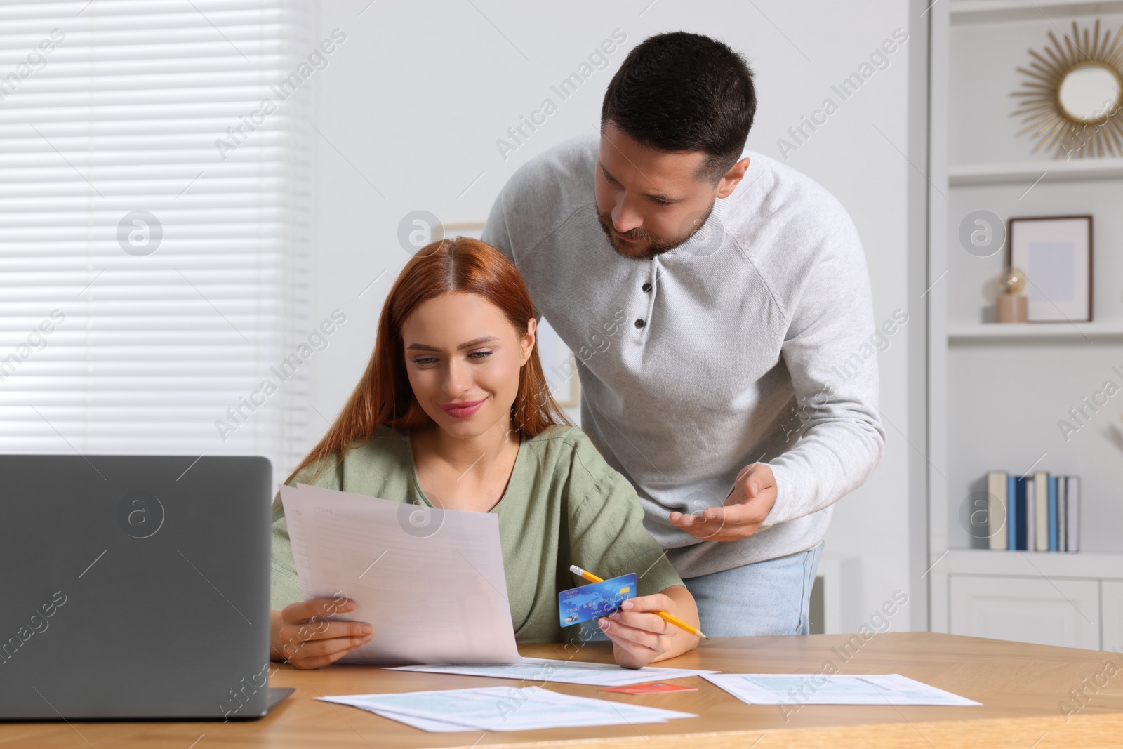 Photo of Couple with credit card using laptop for paying taxes online at home