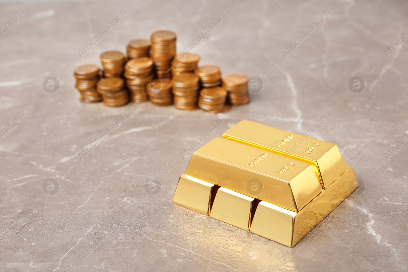 Photo of Stacked gold bars and coins on table. Space for text