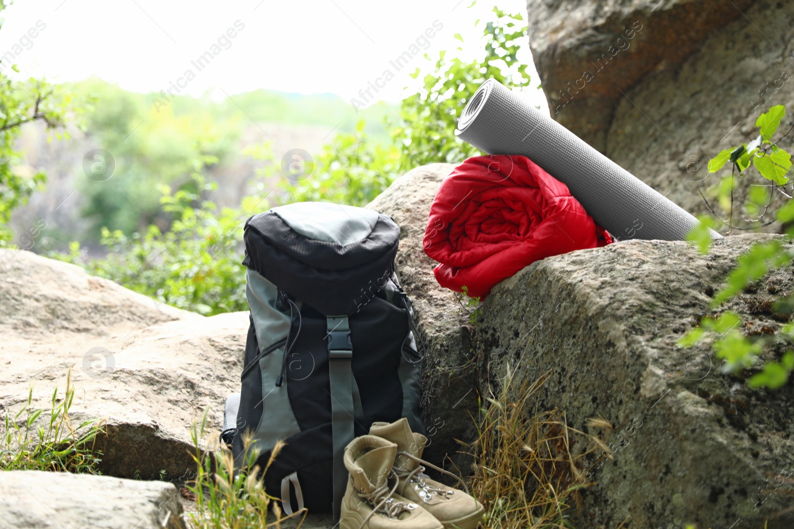 Photo of Rolled sleeping bag, mat, boots and backpack outdoors