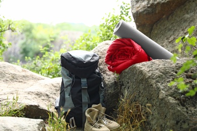 Photo of Rolled sleeping bag, mat, boots and backpack outdoors